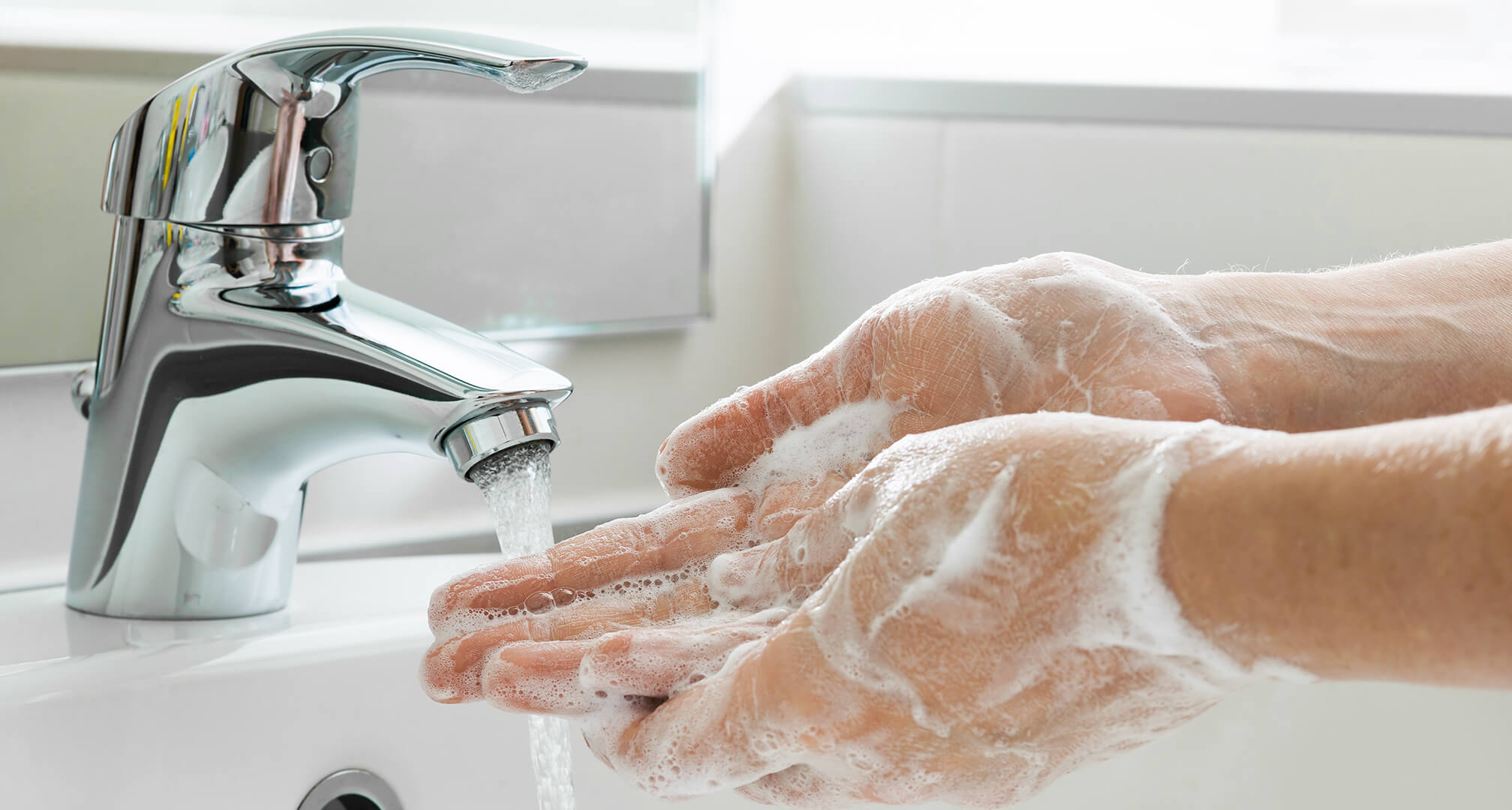 handen wassen met zeep onder de kraan van de gootsteen