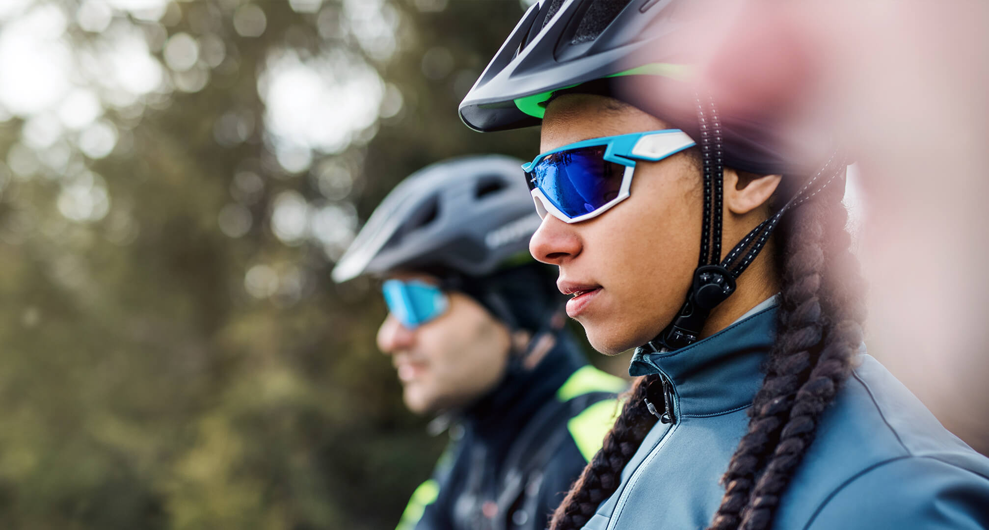 two people wearing cycling sunglasses and helmets