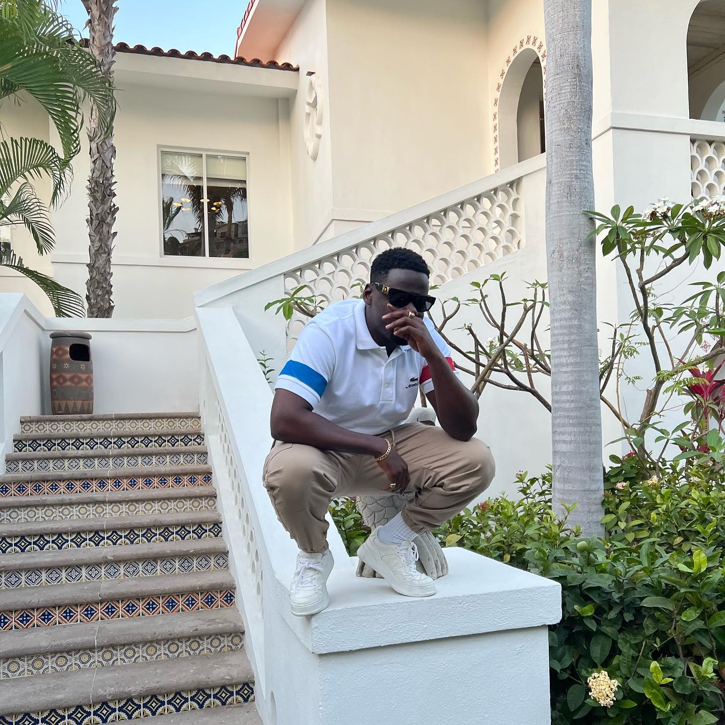 daniel kaluuya squatting on staircase with black sunglasses