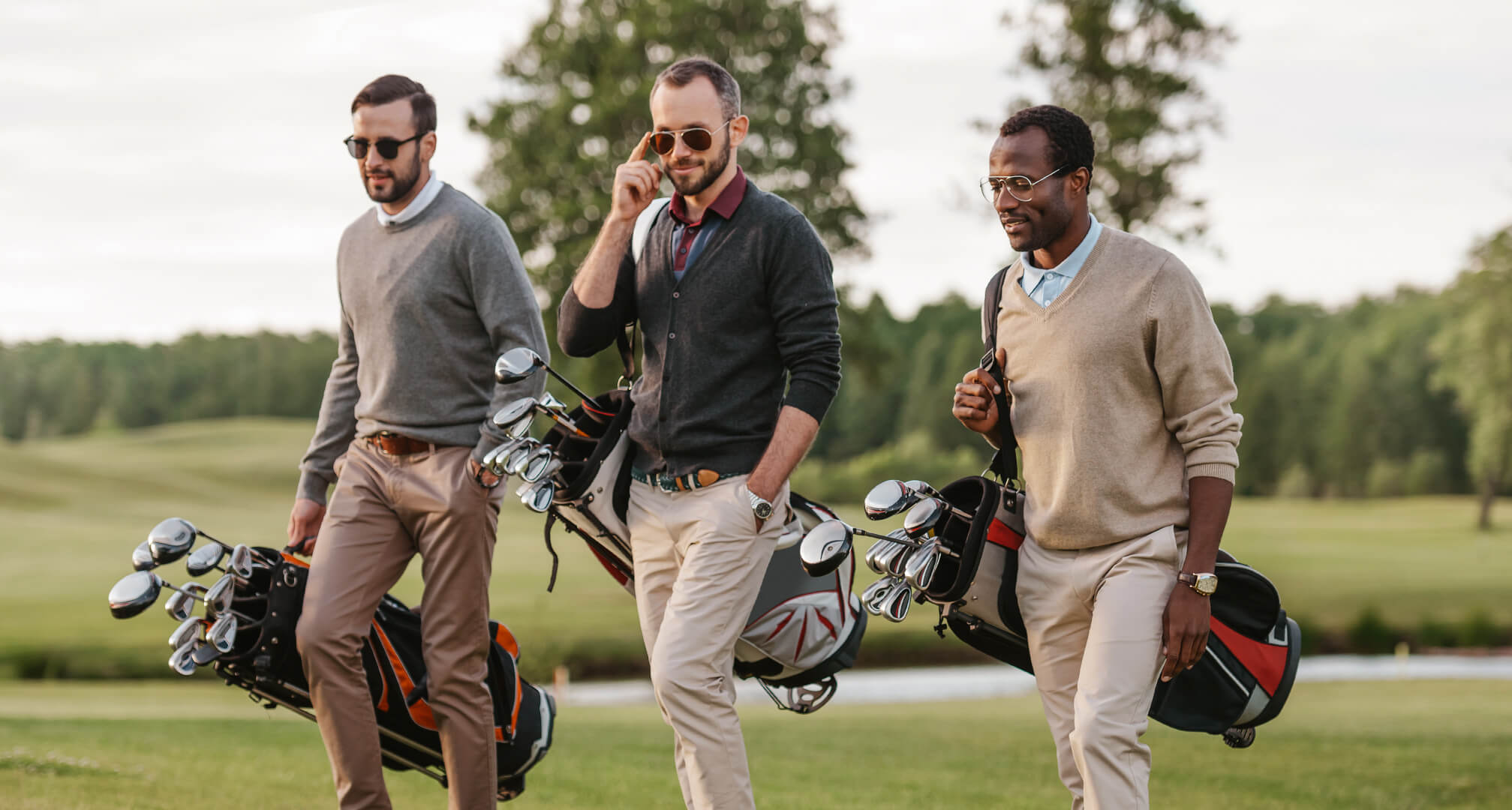 three people golfing with sunglasses and golf bags
