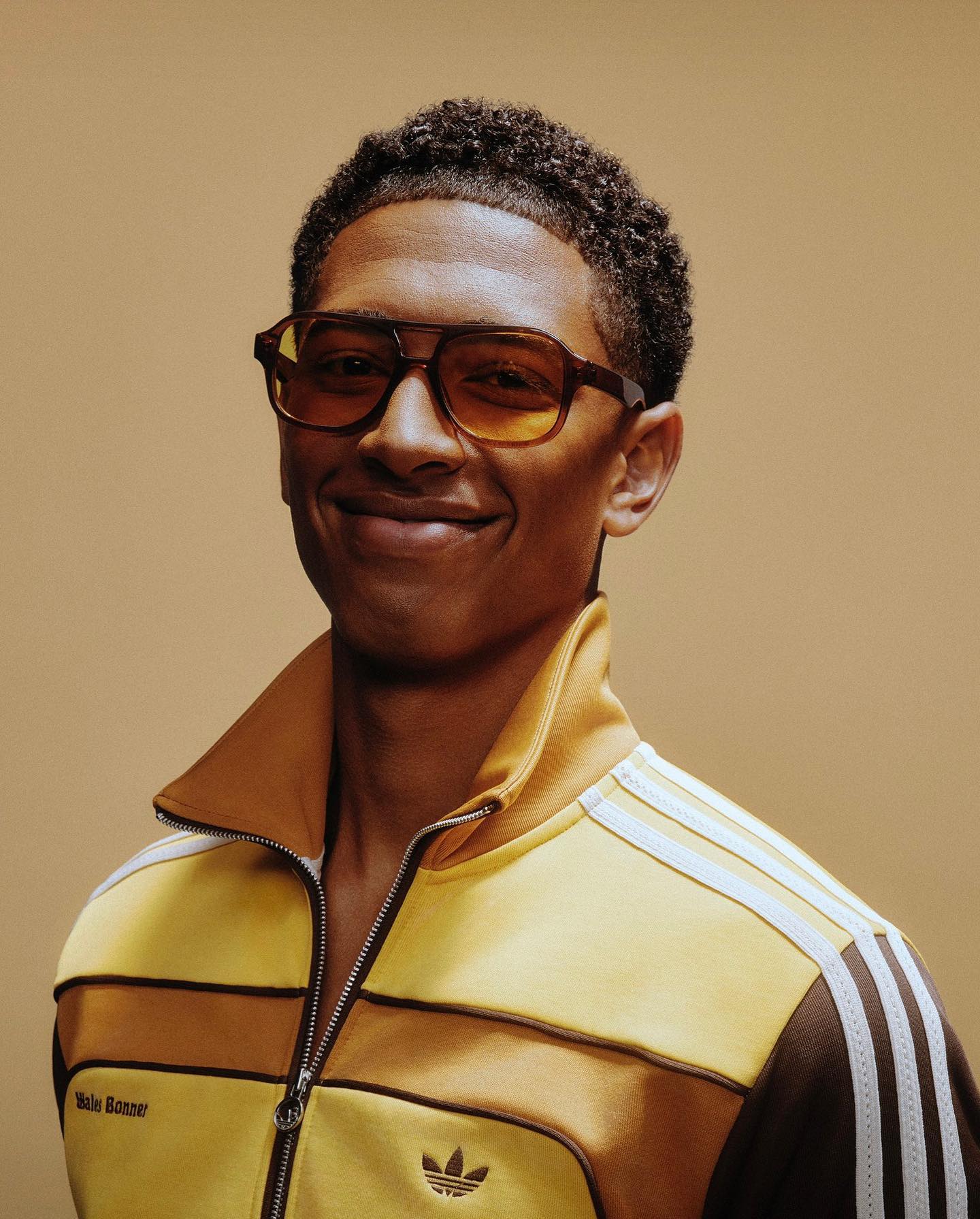 jude bellingham in front of neutral background with brown aviator sunglasses