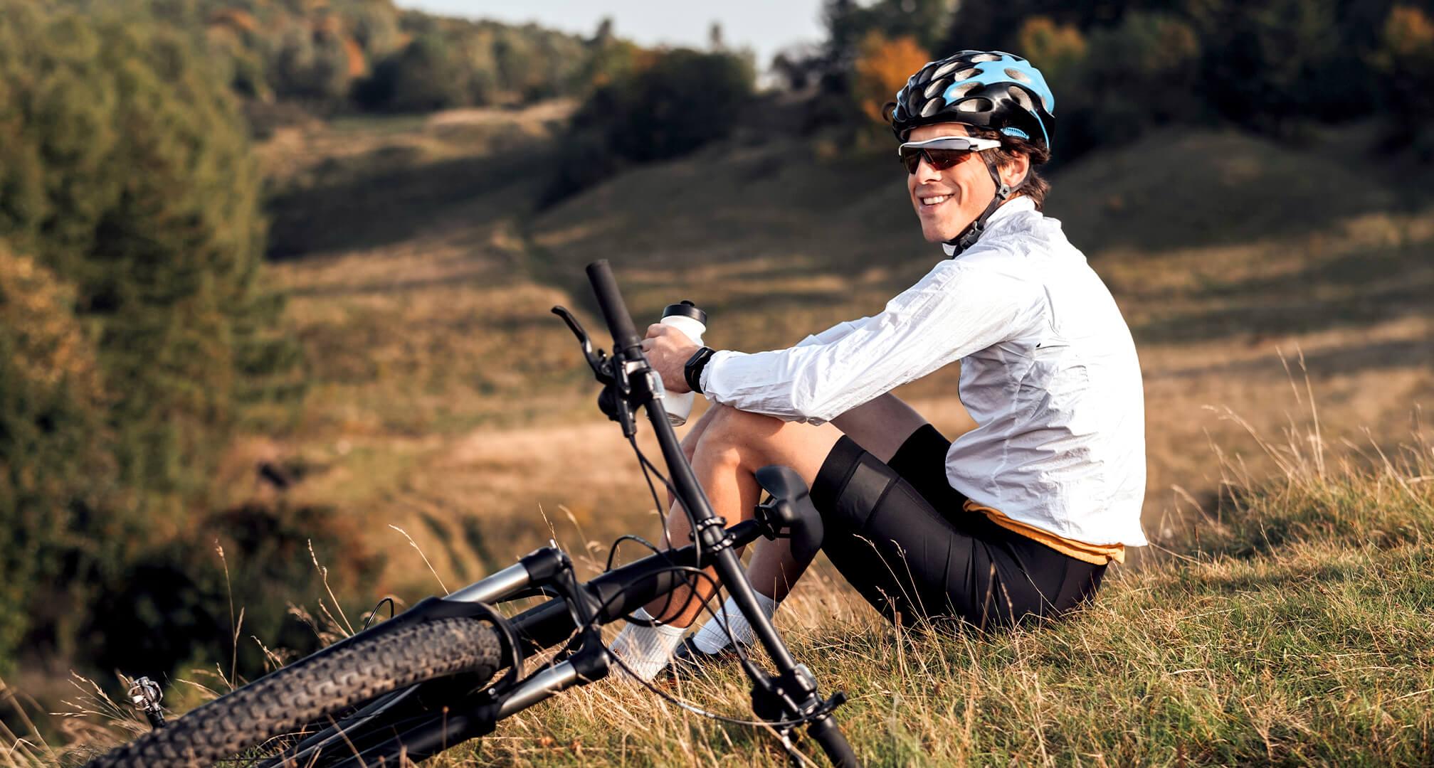 person sitting on hill with mountain bike and wearing sunglasses