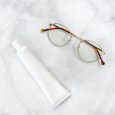 witte tube tandpasta en bril met draadframe op neutrale achtergrond